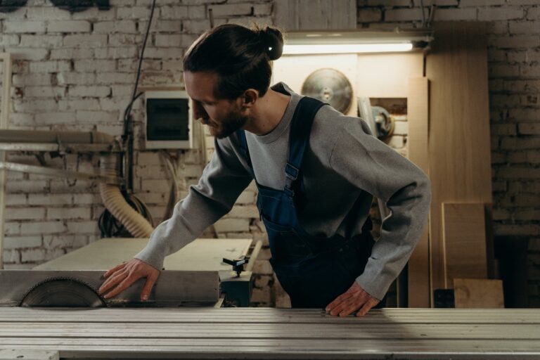 a man in denim jumper touching the sharp saw he is looking